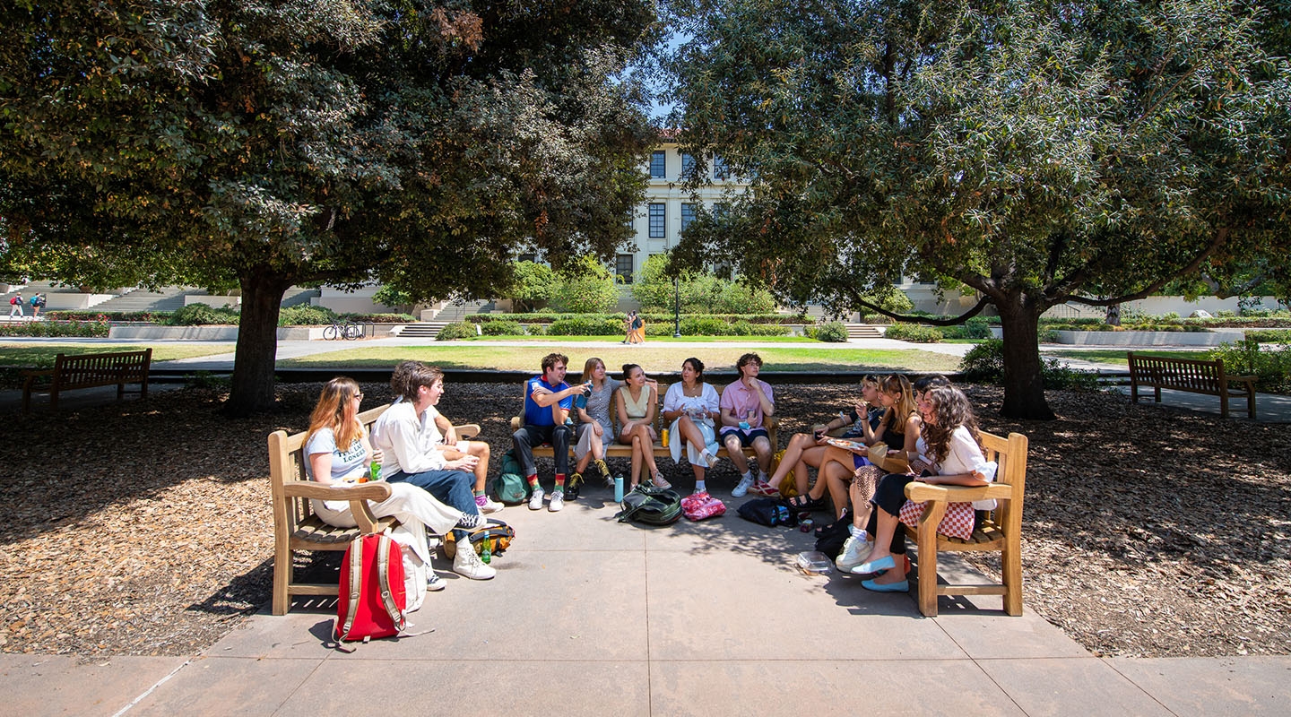 A group of Oxy students lined up on three benches facing each other on the Quad