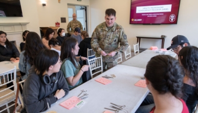 A US Army personnel teaching students about how to perform medical sutures using test kits