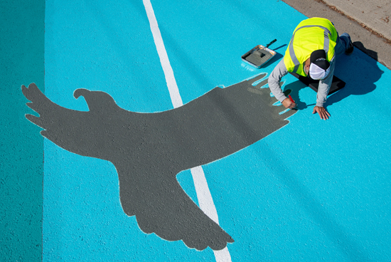 Volunteers from the Oxy community joined a team of artists to paint a 4,000-square-foot asphalt mural on the street in front of Eagle Rock High School and Yosemite Recreation Center as part of a public safety project last January. Photo by Marc Campos