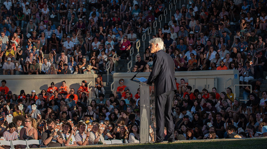 Occidental College President Tom Stritikus stands at a podium in front of a large crowd of people in Remsen Bird Hillside Theater on campus