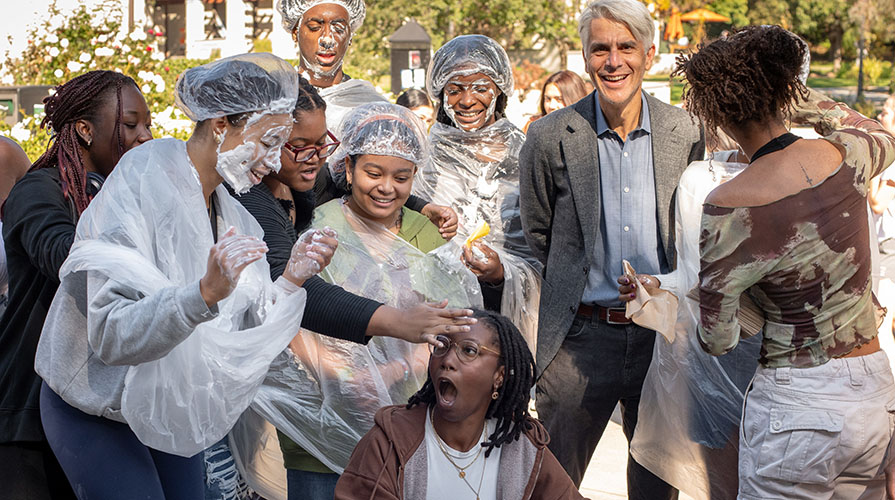 Occidental College students from the Black Students Association playing around as part of a Pie Day fundraiser. President Tom Stritikus joins in.