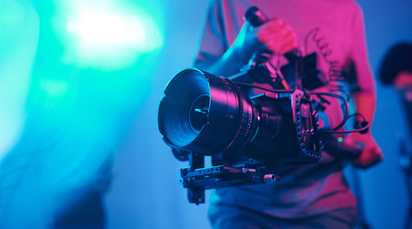 a cameraman holding a fancy film camera with a colored background