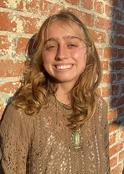 Occidental College student Maggie Schaffzin headshot in front of a brick wall