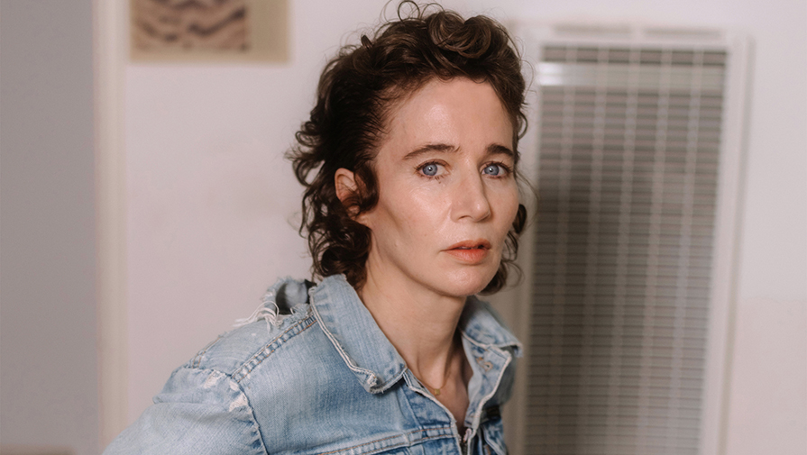 Miranda July headshot wearing a denim collared shirt with curly short hair