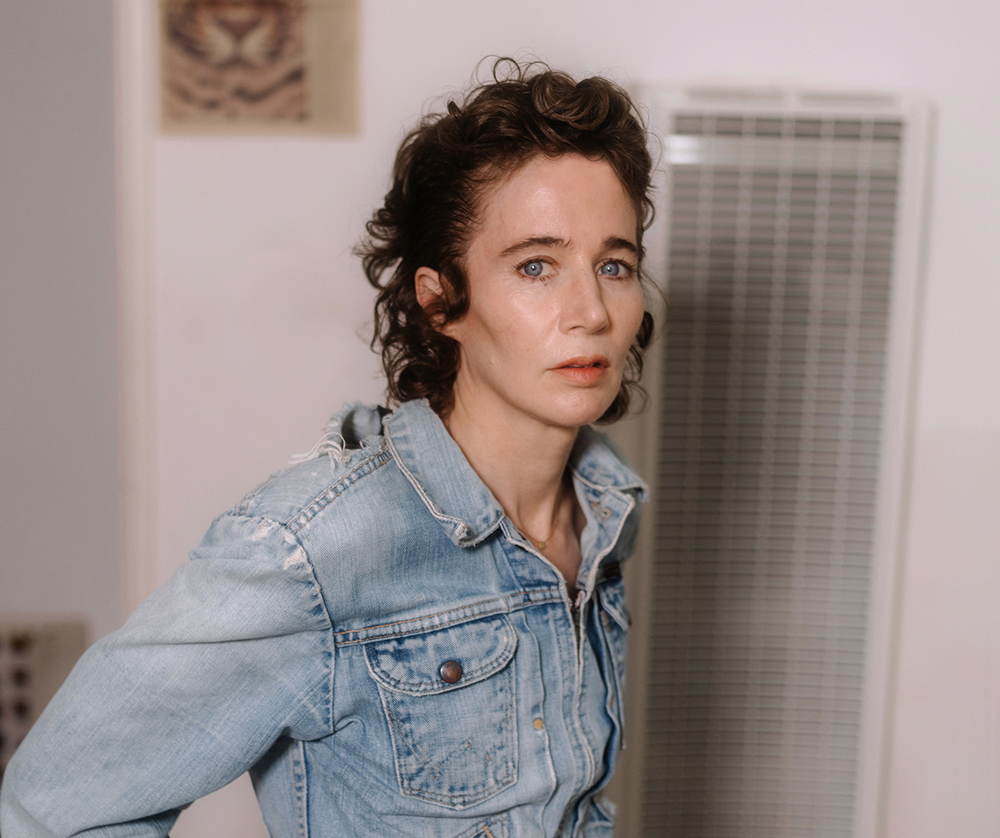 medium color portrait of Miranda July wearing a jean jacket, turned to camera right and looking direct to camera