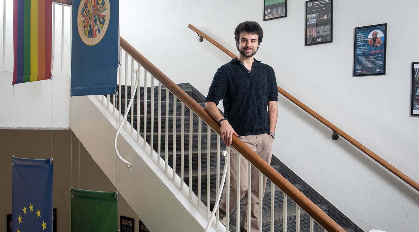 Peter Vartanian on a stairway in Johnson Hall, blue sweater and brown hair