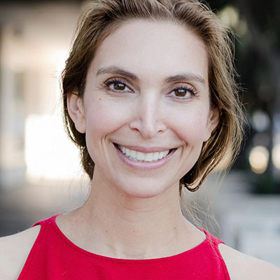 Perrine Mann headshot with a red top and pulled-back hair