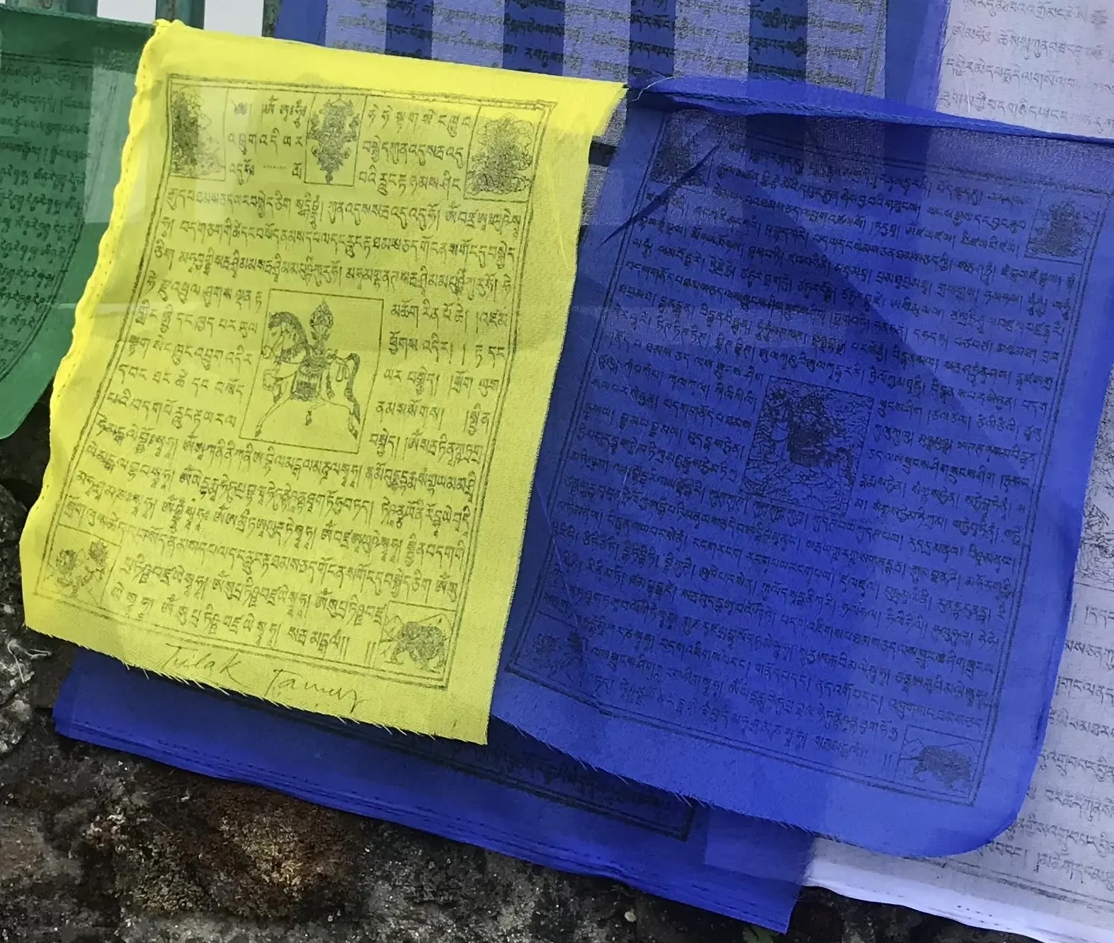 Close up photo of prayer flags, one yellow one blue. 