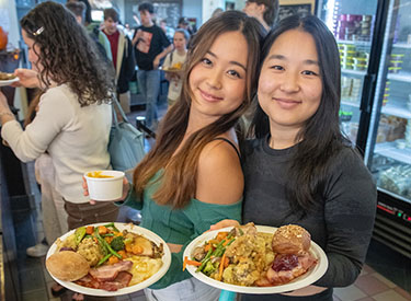 two Occidental students hold up their plates in the Marketplace dining hall