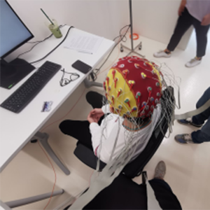 student in a lab with a neuroscience cap and wires on their head