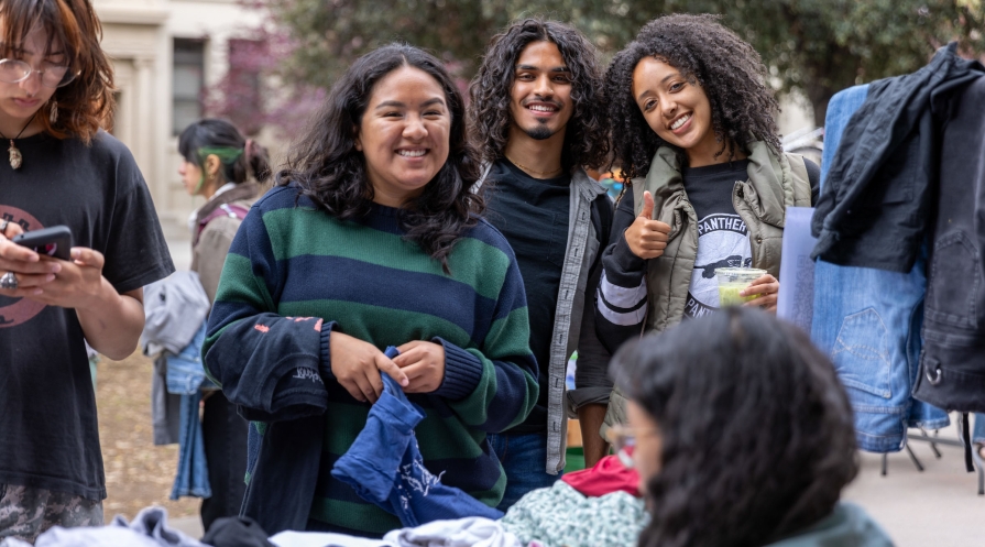 Three Occidental college students huddled together smiling, one flashing the peace sign