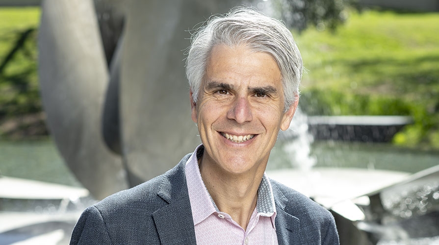 Occidental College President Tom Stritikus standing in front of Gilman Fountain