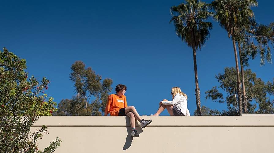 Two Occidental College students sit on a wall on the Los Angeles campus