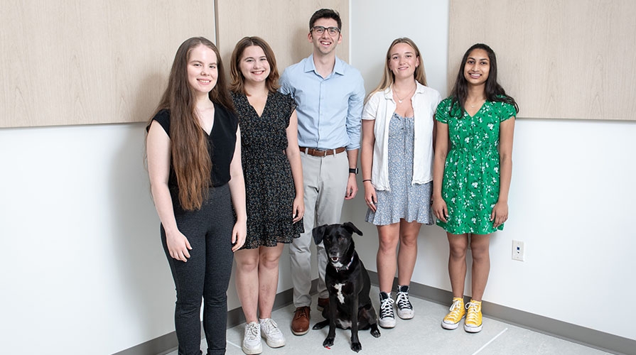 Occidental College professor Zach Silver stands with his undergraduate research assistants and a black dog