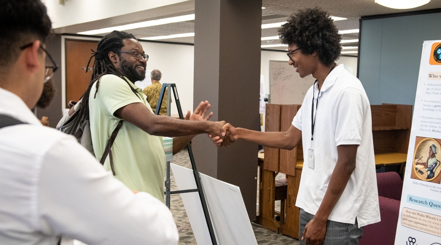 Occidental Professor James Ford shaking hands with a student at the Summer Research Conference on campus