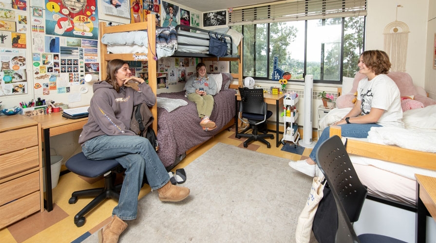 students hanging out on chairs in their dorm room, talking