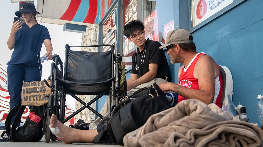 an Occidental College student works on a street medicine team offering healthcare to an unhoused man