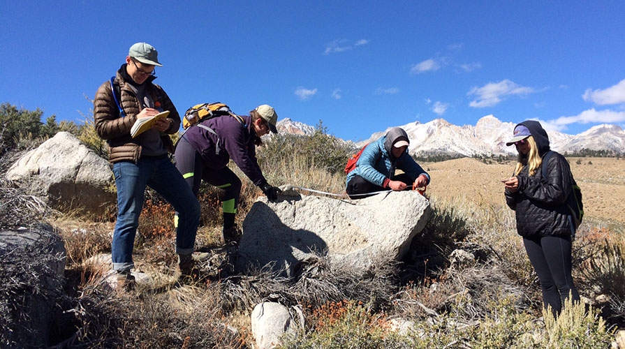 Occidental College students conducting geology research in the field with beautiful mountains in the background