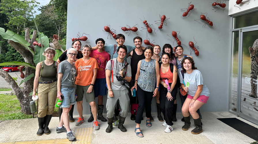 Richter students posing as a group in Costa Rica with an ant mural on the wall behind them