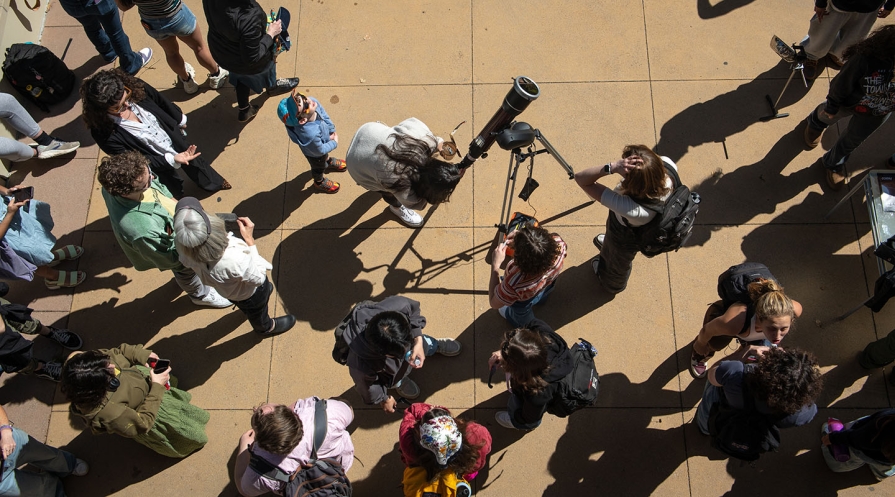 Occidental community members viewing the solar eclipse with a telescope