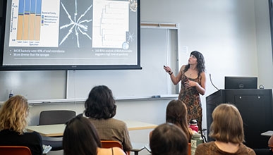 a student giving a lecture looking up at a projection screen with students looking on