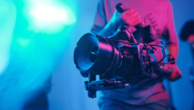 a cameraman holding a fancy film camera with a colored background