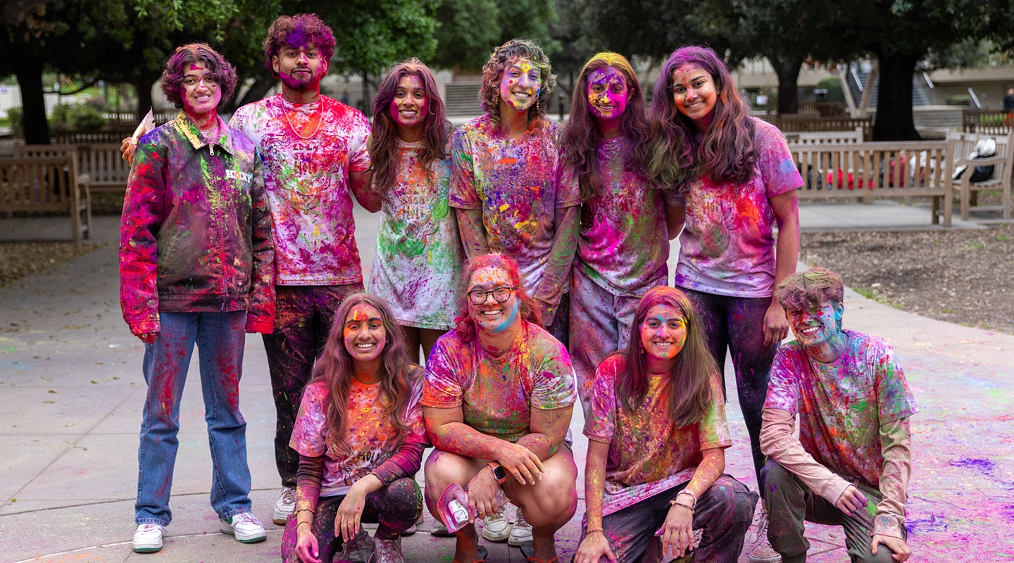 Occidental College students covered in brightly colored powder at a Holi celebration on campus