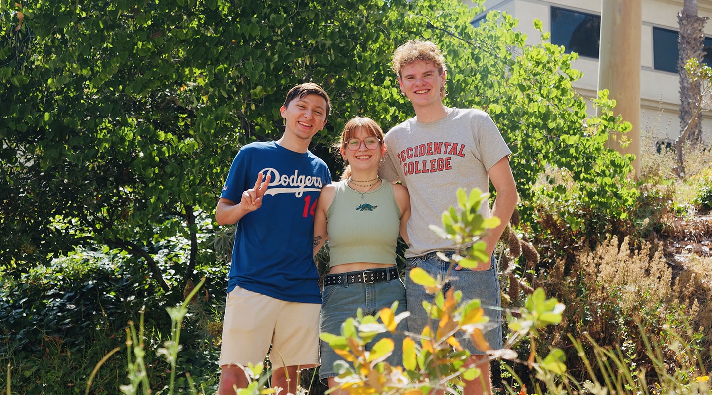 three students pose together in Oxy's Microforest on campus