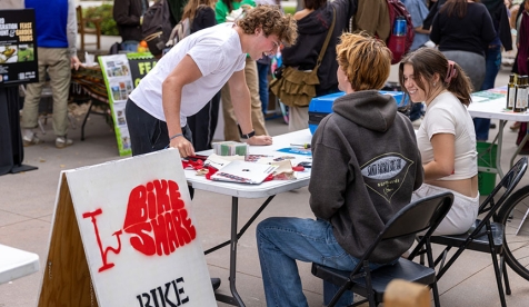 Bike Share students talking to passers-by at a table in the Quad on the Occidental College campus