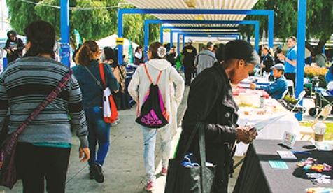 A group of people at an informational fair, looking at tables and talking to others