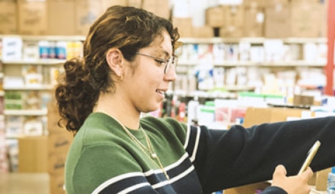 a young woman looking at boxes in the store and looking at her cell phone