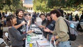 oxy students at a table at the involvement fair on the quad smiling and laughing