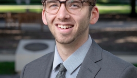 Dr. Zachary Silver in front of plants and memorial