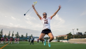 An Occidental College lacrosse player jumps into the air joyfully after a team victory