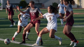 Four women playing soccer on turf field during daylight