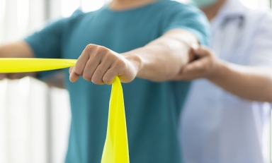 a physical therapy patient stretches using a resistance band