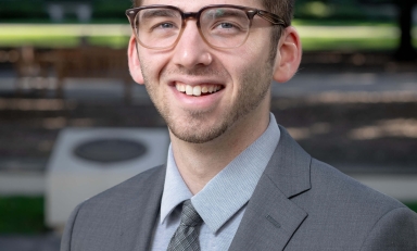 Dr. Zachary Silver in front of plants and memorial