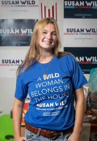 Cady Carr, Oxy student, standing with a blue campaign tshirt for Susan Wild