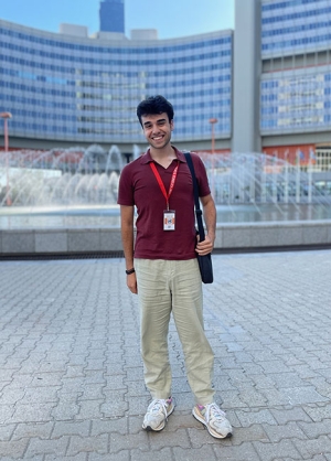 Peter Vartanian in a burgundy shirt and khakis stands in an urban square