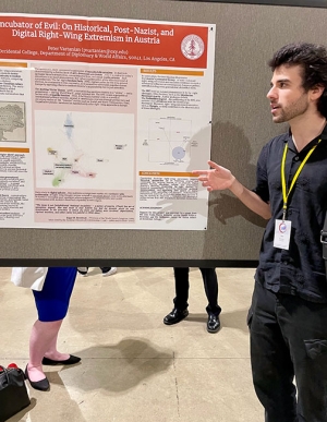 Peter Vartanian all in black, presenting a research poster at a research conference