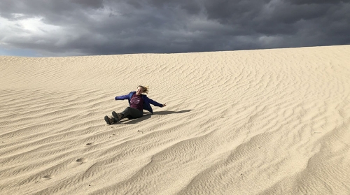 Occidental College alumna Lauren Berger sitting on sand ripples in the Mojave Desert