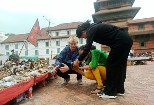 Truman Urness works with two others adjusting his camera on a street in Nepal